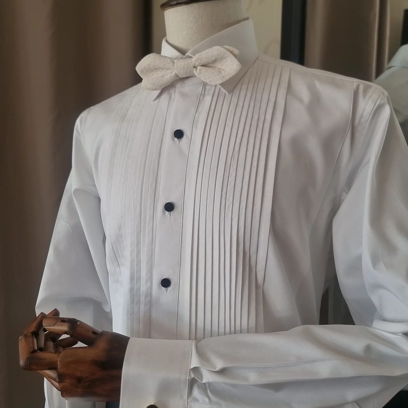 A pleated white tuxedo shirt with black studs and an ivory bow tie