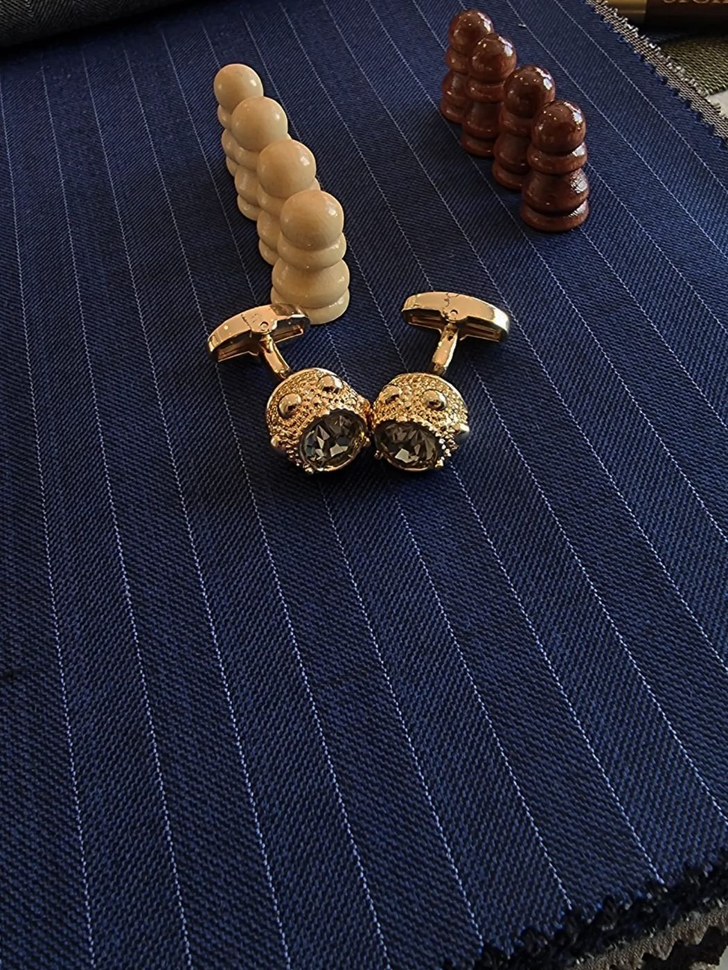 Gold cuff links on navy chalk-stripe cloth