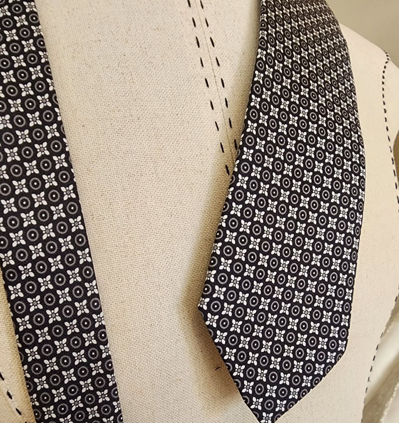 A black and white printed silk tie on a stand