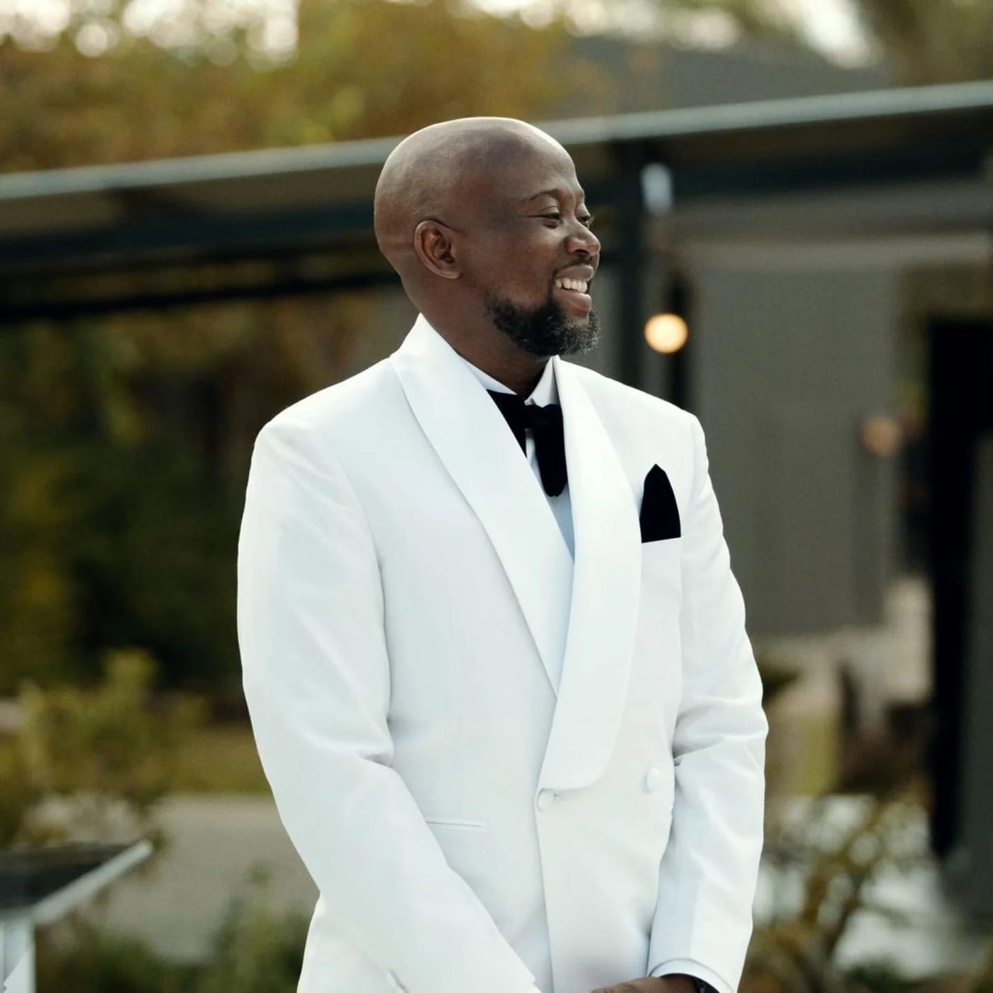 A groom in an ivory shawl-collar dinner jacket