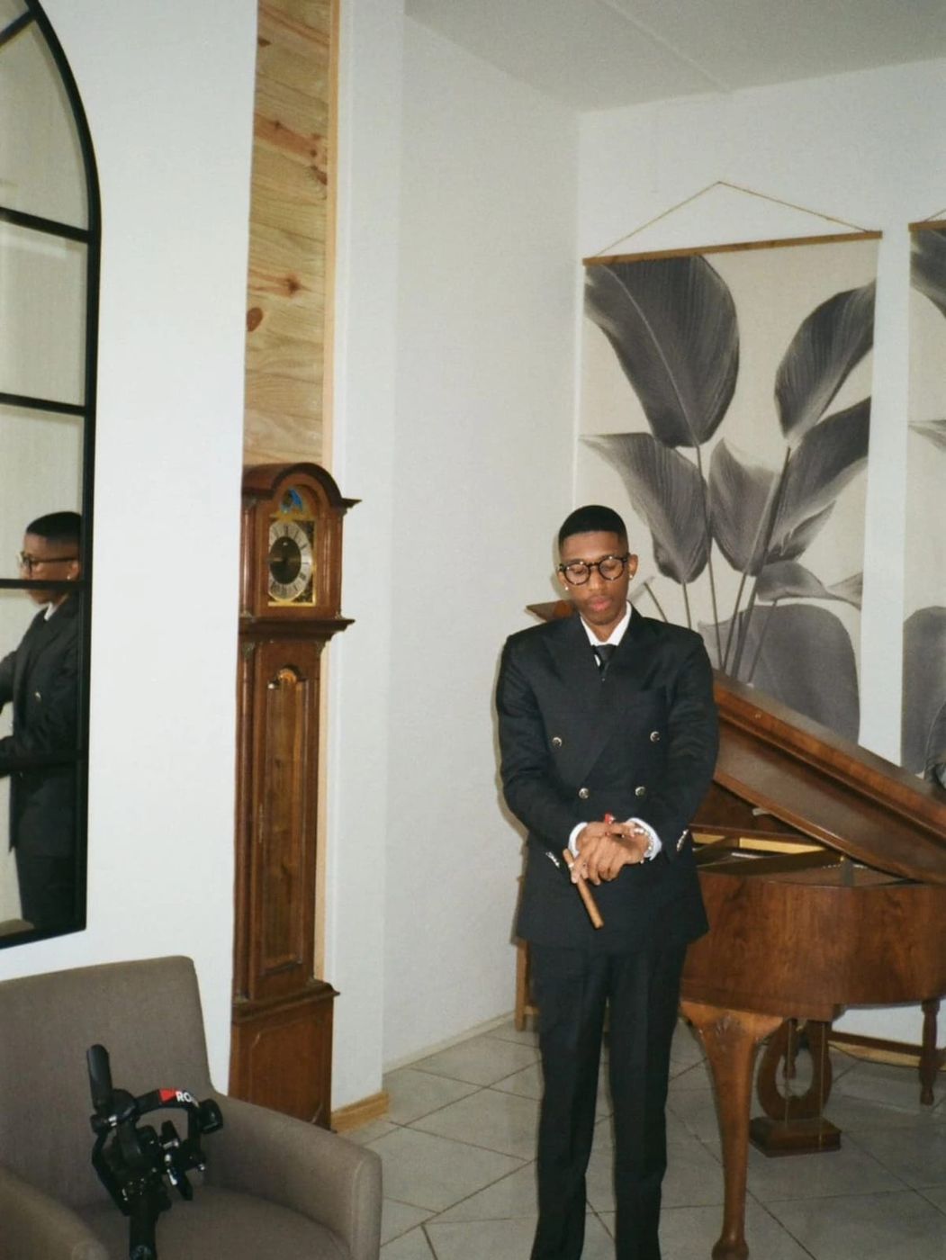 A matric dance suit in black, worn with glasses