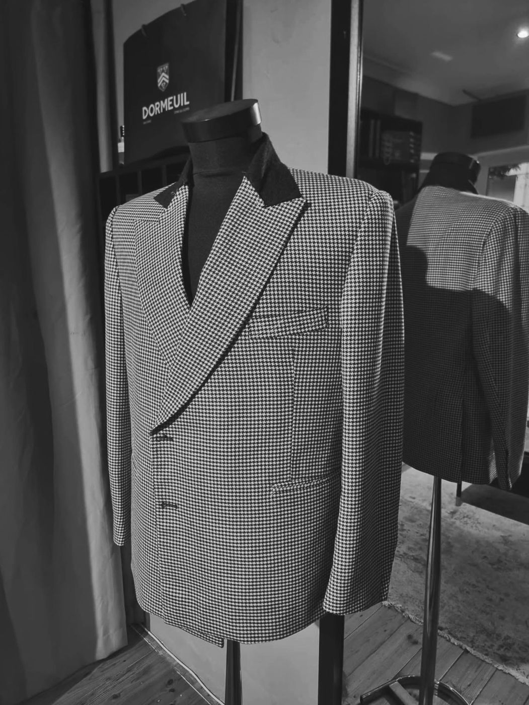 A houndstooth peak-lapel jacket with a black melton under-collar in the studio