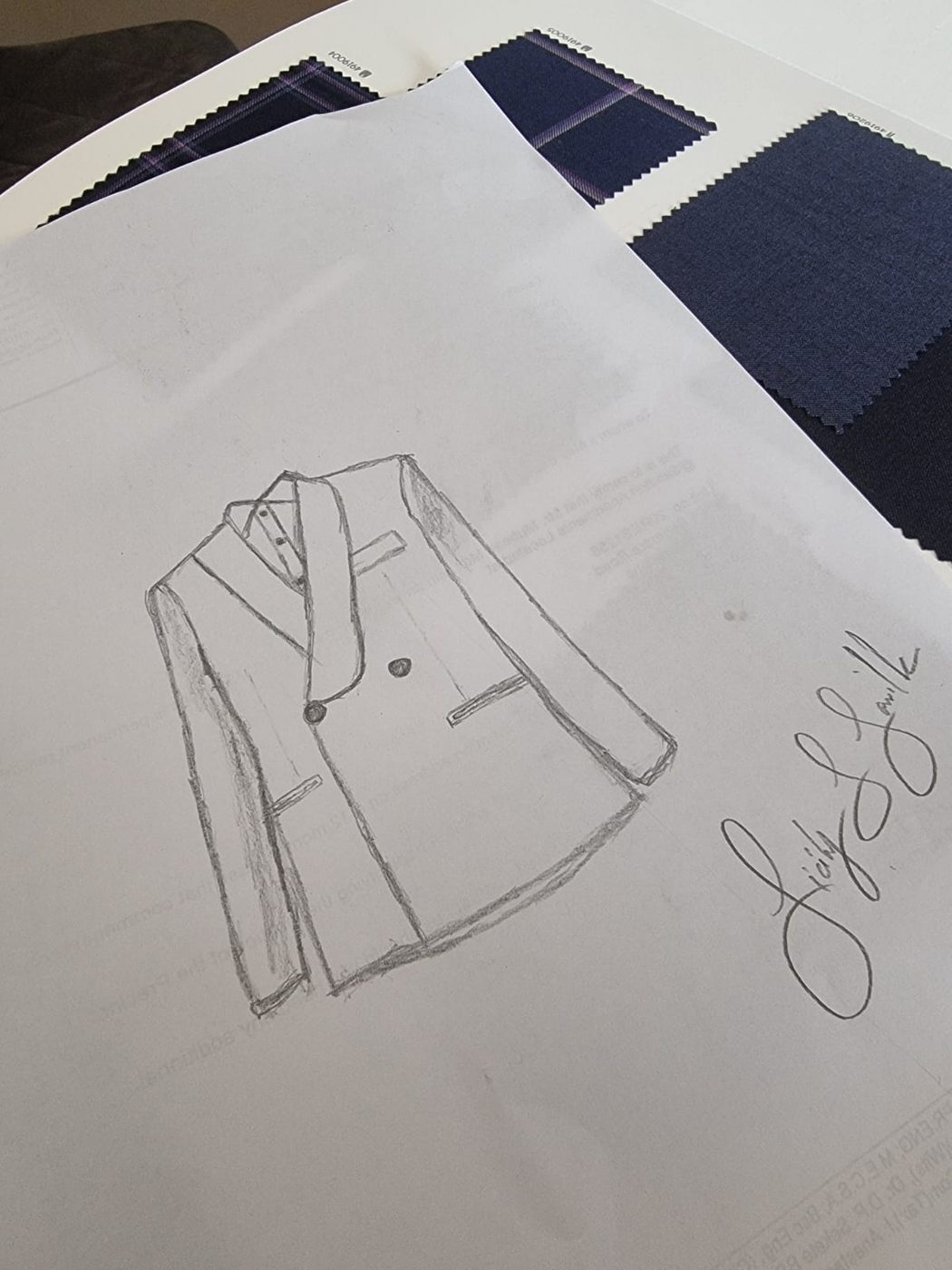 A pencil sketch of a double-breasted jacket on navy cloth swatches