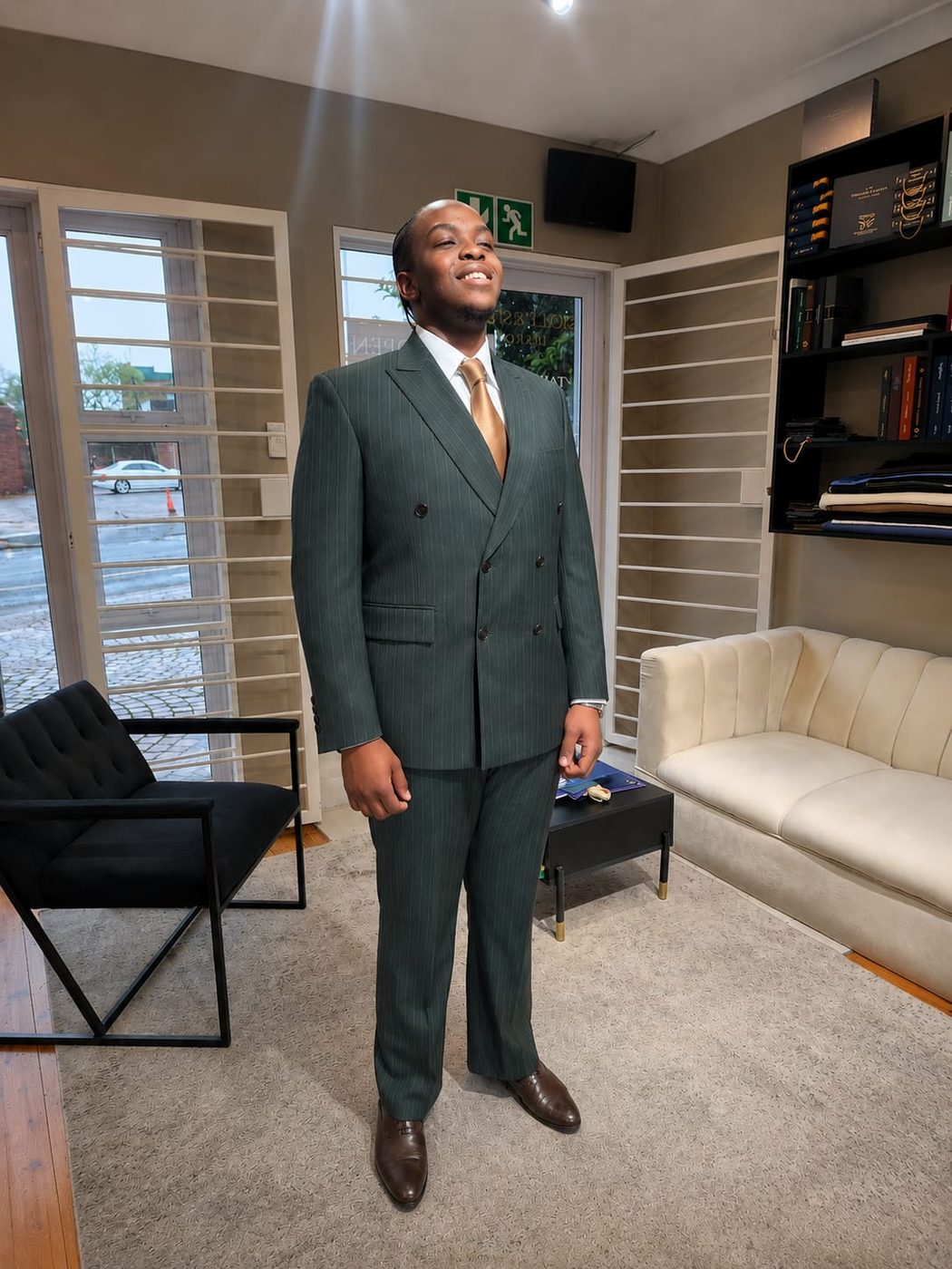 A client in his finished green double-breasted pinstripe suit in the studio