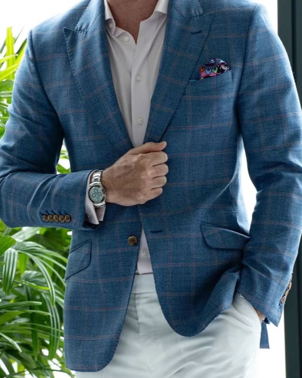 A blue windowpane-check sports coat worn with white trousers